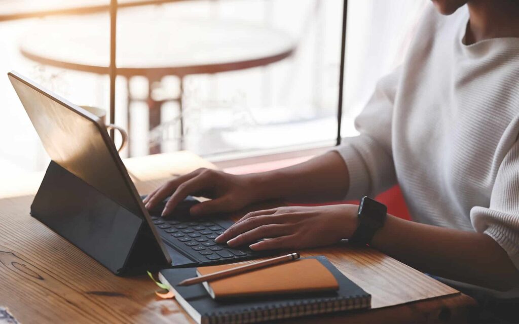Side view of a woman typing on tablet keyboard