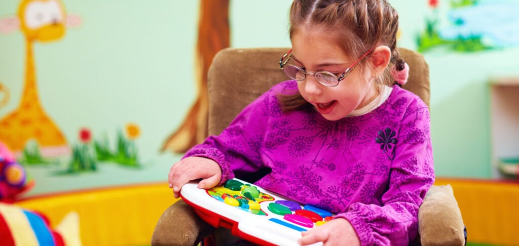 girl in wheelchair playing with developing toy in kindergarten for children with special needs