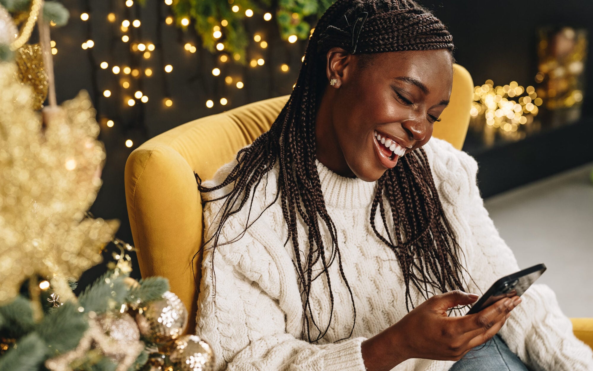 Young African American woman using her phone at home decorated for Christmas season close up
